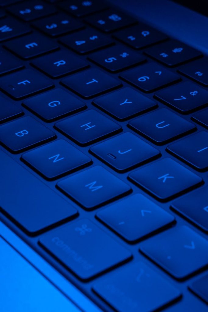 Close-up image of a laptop keyboard illuminated with blue light, showcasing modern technology design.